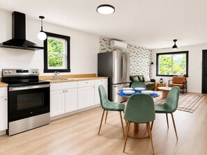 Eine moderne Küche mit Herd, Backofen, Spüle und Kühlschrank. Ein Essbereich mit Tisch und Stühlen ist ebenfalls vorhanden.