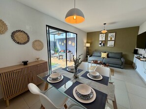 Una sala de estar moderna con una mesa de comedor de vidrio, un sofá y un televisor.