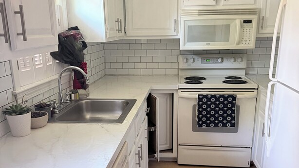 A compact kitchen with white cabinets, a stainless steel sink, a microwave, an oven, and a refrigerator. - 2-bedroom townhome in terrific Attleboro  close to Gillette and Foxwoods (Attleboro)