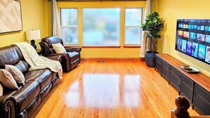 A living room with a brown leather sofa, a large flat-screen TV, and a potted plant. - Townhome 3 bedroom 2 bath with Parking - near McCormick Place , Chinatown Sox (Chicago)