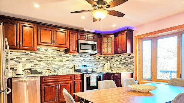 A kitchen with wooden cabinets, a stainless steel refrigerator, a microwave, and a dining table with chairs. - Townhome 3 bedroom 2 bath with Parking - near McCormick Place , Chinatown Sox (Chicago)