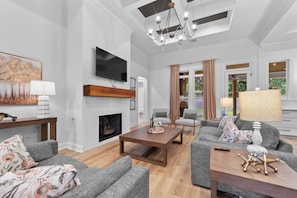 A modern living room with a fireplace, grey sofas, a coffee table, and a TV mounted on the wall.