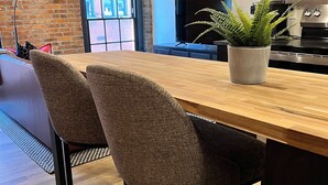 A kitchen with a wooden countertop, two upholstered chairs, a potted plant, a television, and a stainless steel oven. - Brick and Bed - Riverfront Loft - Walk to Arch (St. Louis)