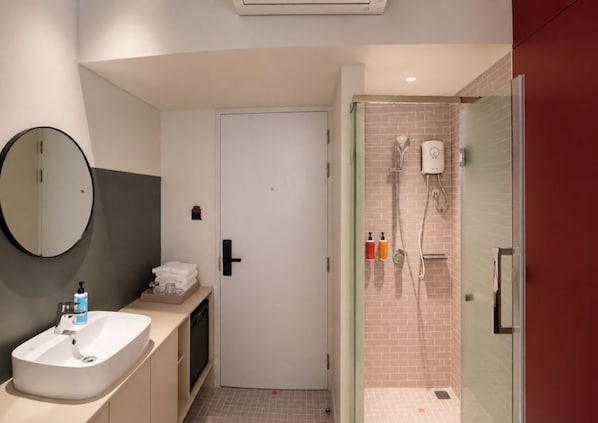 Un baño moderno con lavamanos, espejo y zona de ducha.