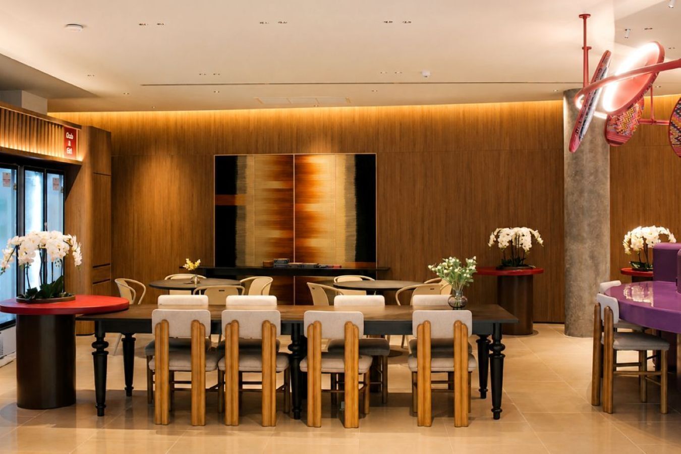 Un comedor moderno con una mesa larga, sillas y un cuadro abstracto grande en la pared.