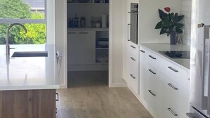 Une cuisine moderne avec des meubles blancs, un four encastré et un réfrigérateur.
