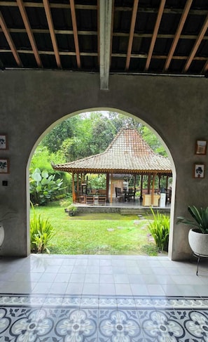 An arched doorway leading to a gazebo with a tiled roof, surrounded by greenery. - nDalem Riyartan Villa Kaliurang (Sleman)