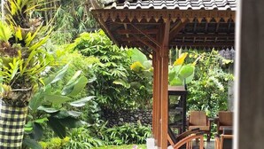 A garden with a wooden gazebo, lush greenery, and a checkered planter. - nDalem Riyartan Villa Kaliurang (Sleman)