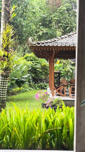A garden with a wooden gazebo, lush greenery, and a checkered planter. - nDalem Riyartan Villa Kaliurang (Sleman)