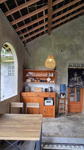A rustic kitchen with wooden cabinets, a hanging light fixture, and a tiled floor. - nDalem Riyartan Villa Kaliurang (Sleman)