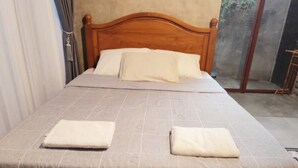 A single bed with a wooden headboard, a grey checkered bedspread, and two white pillows. - nDalem Riyartan Villa Kaliurang (Sleman)