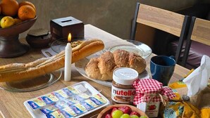A breakfast table with bread, pastries, fruit, and condiments. - nDalem Riyartan Villa Kaliurang (Sleman)