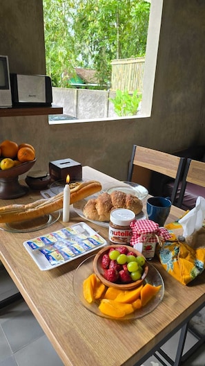 A breakfast table with bread, pastries, fruit, and condiments. - nDalem Riyartan Villa Kaliurang (Sleman)