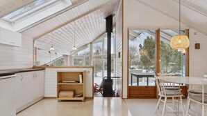 A modern kitchen with a skylight, a dining area with white chairs, and a large window offering a view of the outdoors. - 4 Star Holiday Home in Nykobing Sj (Nykobing Sjaelland)
