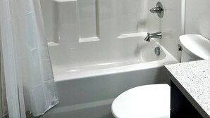 Um banheiro moderno com box de vidro, banheira, vaso sanitário e pia.