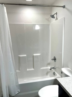 A modern bathroom with a glass shower enclosure, a bathtub, a toilet, and a sink. - Brick & Bed - Riverfront Studio - Walk to Arch (St. Louis)