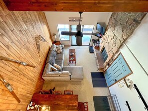 Ein gemütliches Wohnzimmer mit Holzboden, einer grauen Couch, einem Couchtisch und einer Steinwand.