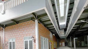 Um edifício em estilo industrial com teto alto, grandes janelas e fachada revestida de azulejos.