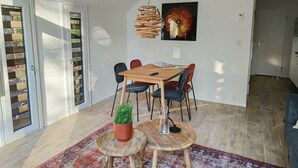 Zona pranzo moderna con tavolo in legno, sedie, lampadario e pianta in vaso.