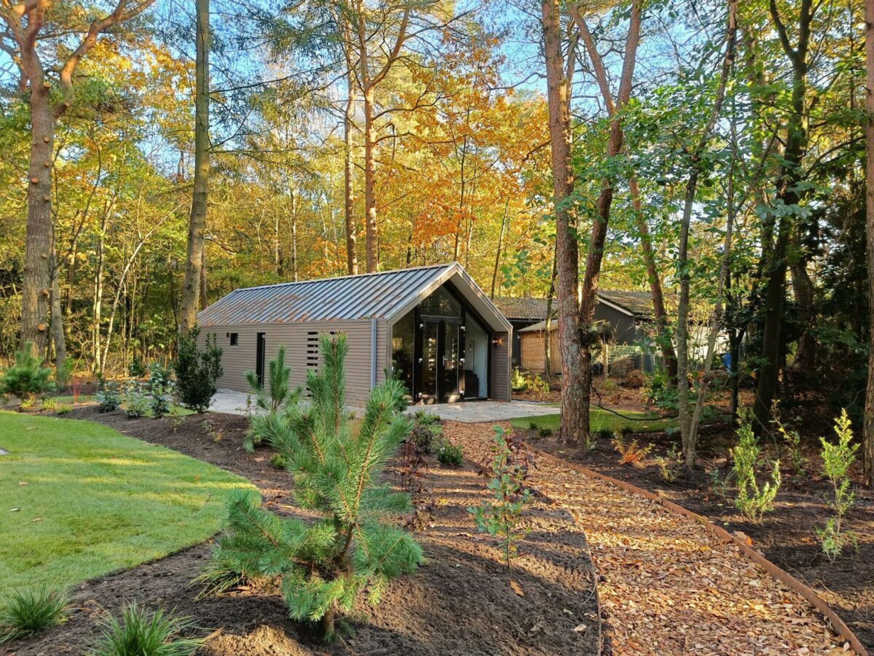 A small cabin with a sloped roof, surrounded by a forest.