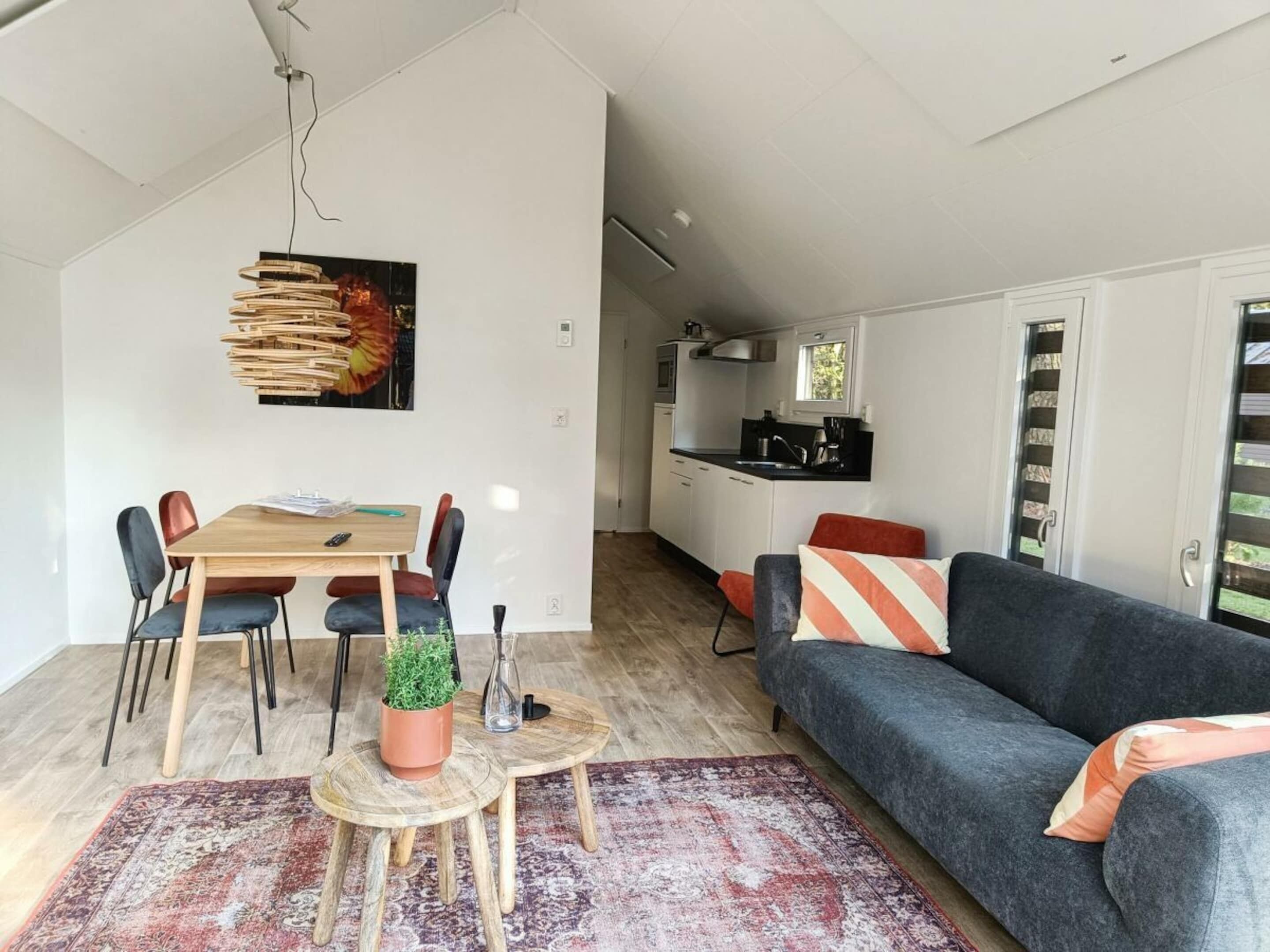 Un espace de vie moderne comprenant un coin repas, un canapé, une cuisine et une grande fenêtre.