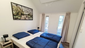 Una camera da letto con un letto, un comodino, una lampada e un'ampia finestra con tende.