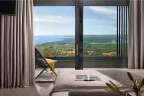 A bedroom with a large window, a bed, a chair, and a plant. -  Villa Panoramica (Rabac)