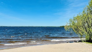 A beach with a sandy shore, a body of water, and a tree on the right.