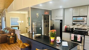 A modern kitchen with a central island, stainless steel appliances, and a bar area with stools.