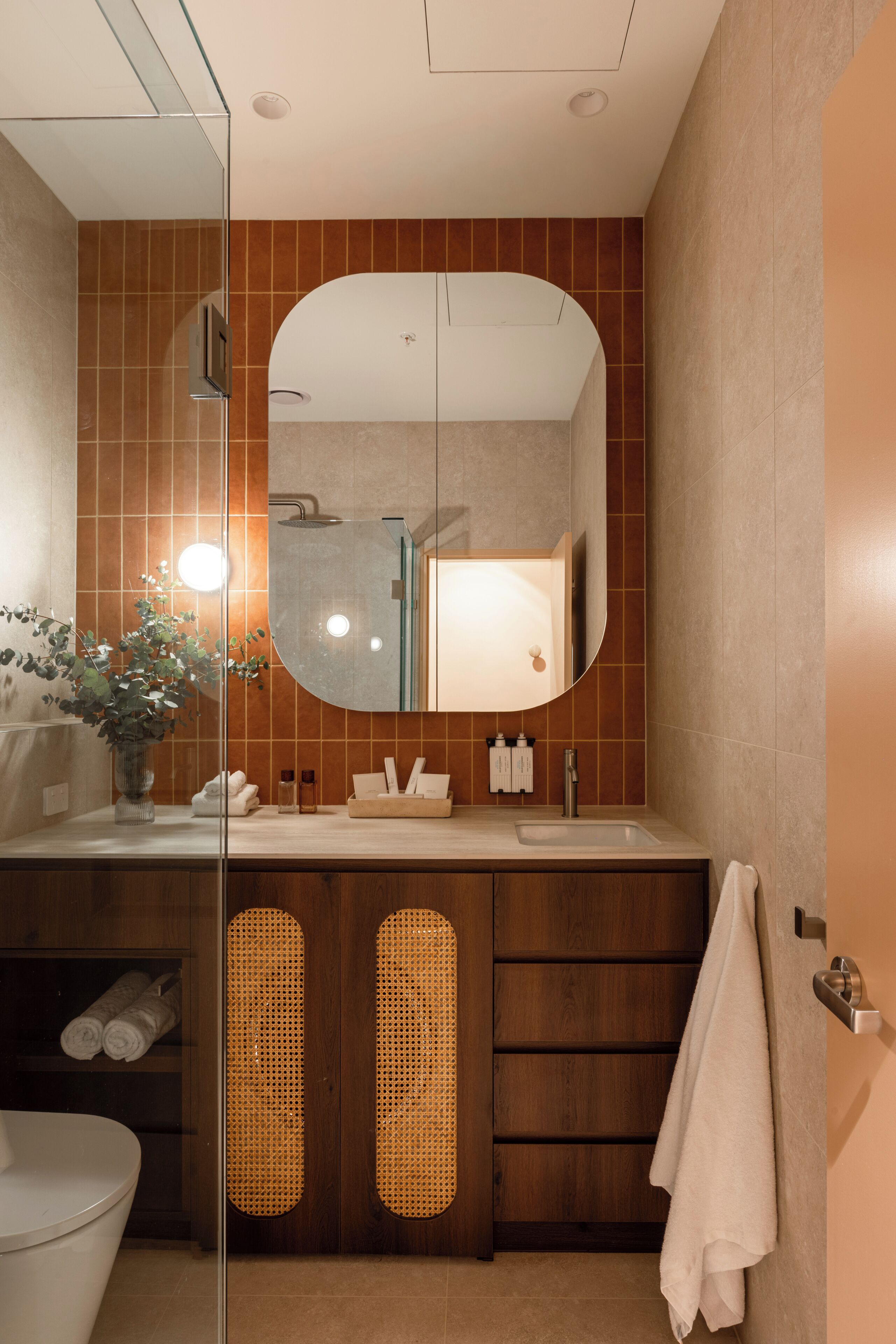 A modern bathroom with a large mirror, a shower, and a vanity with a sink.
