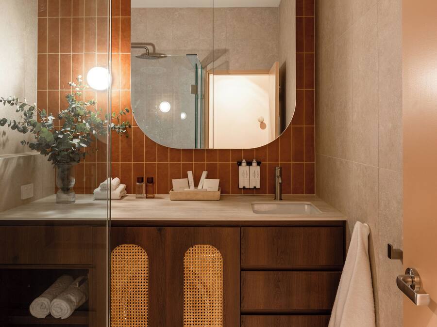 A modern bathroom with a large mirror, a shower, and a vanity with a sink.