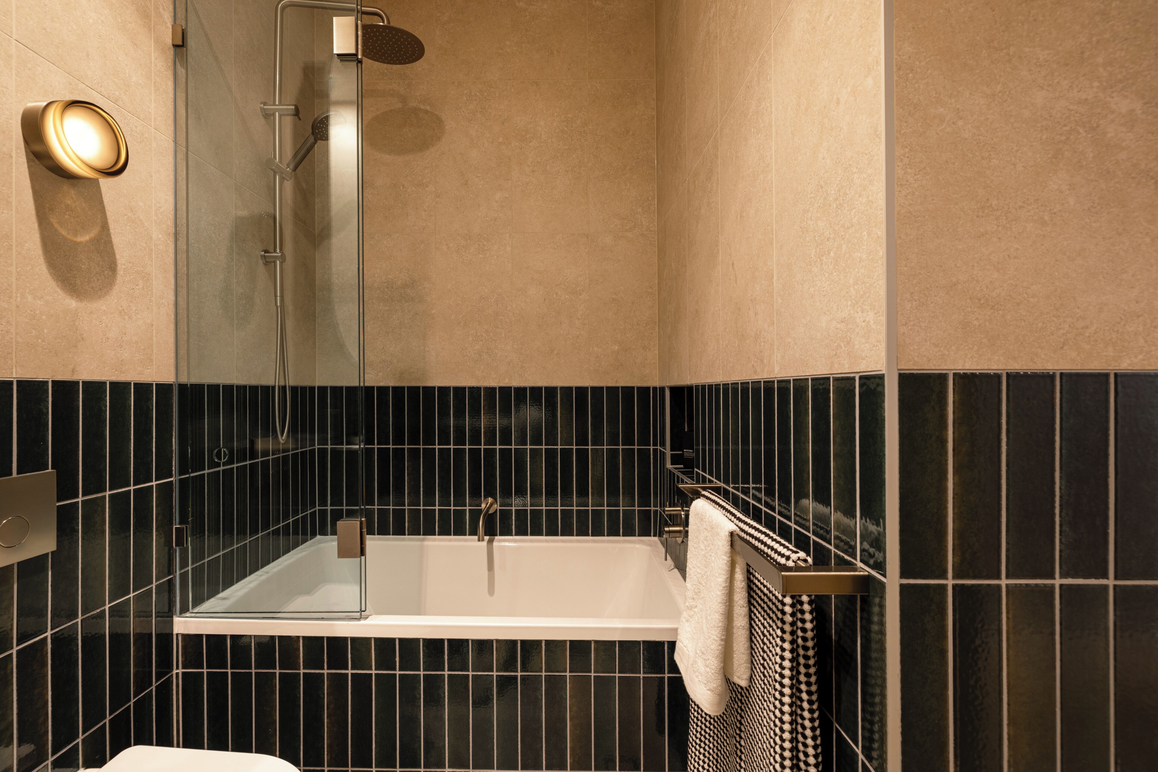 Un baño moderno con ducha de vidrio, una bañera blanca y un perchero para toallas.