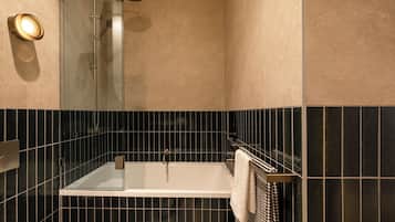 A modern bathroom with a glass-enclosed shower, a white bathtub, and a towel rack.