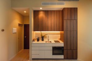 Una cocina compacta con armarios de madera, un lavamanos empotrado y una estufa.