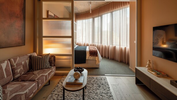 A modern living room with a sofa, coffee table, and a TV mounted on the wall. - The Lane House (Melbourne)