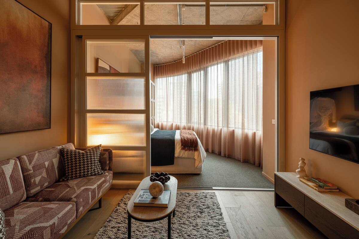 A modern living room with a sofa, coffee table, and a TV mounted on the wall.