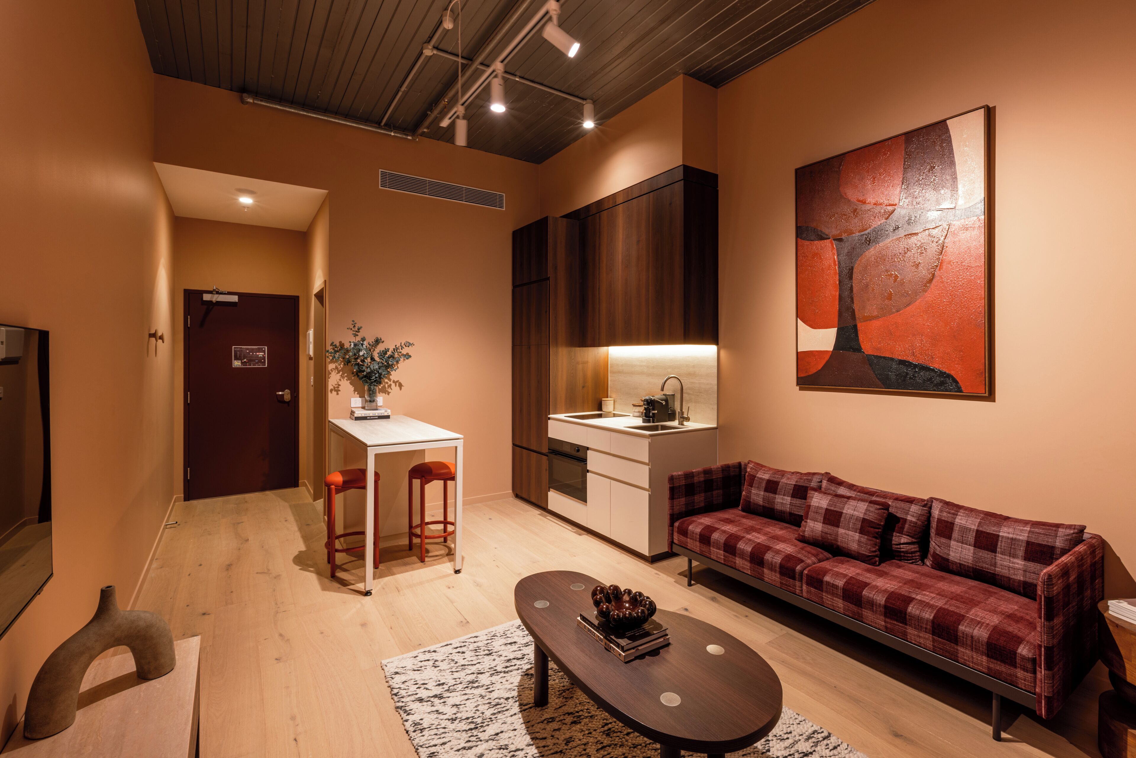 A modern living room with a sofa, a coffee table, a kitchen area, and a dining table.