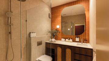 A modern bathroom with a glass-enclosed shower, a toilet, a vanity with a mirror, and a sink.