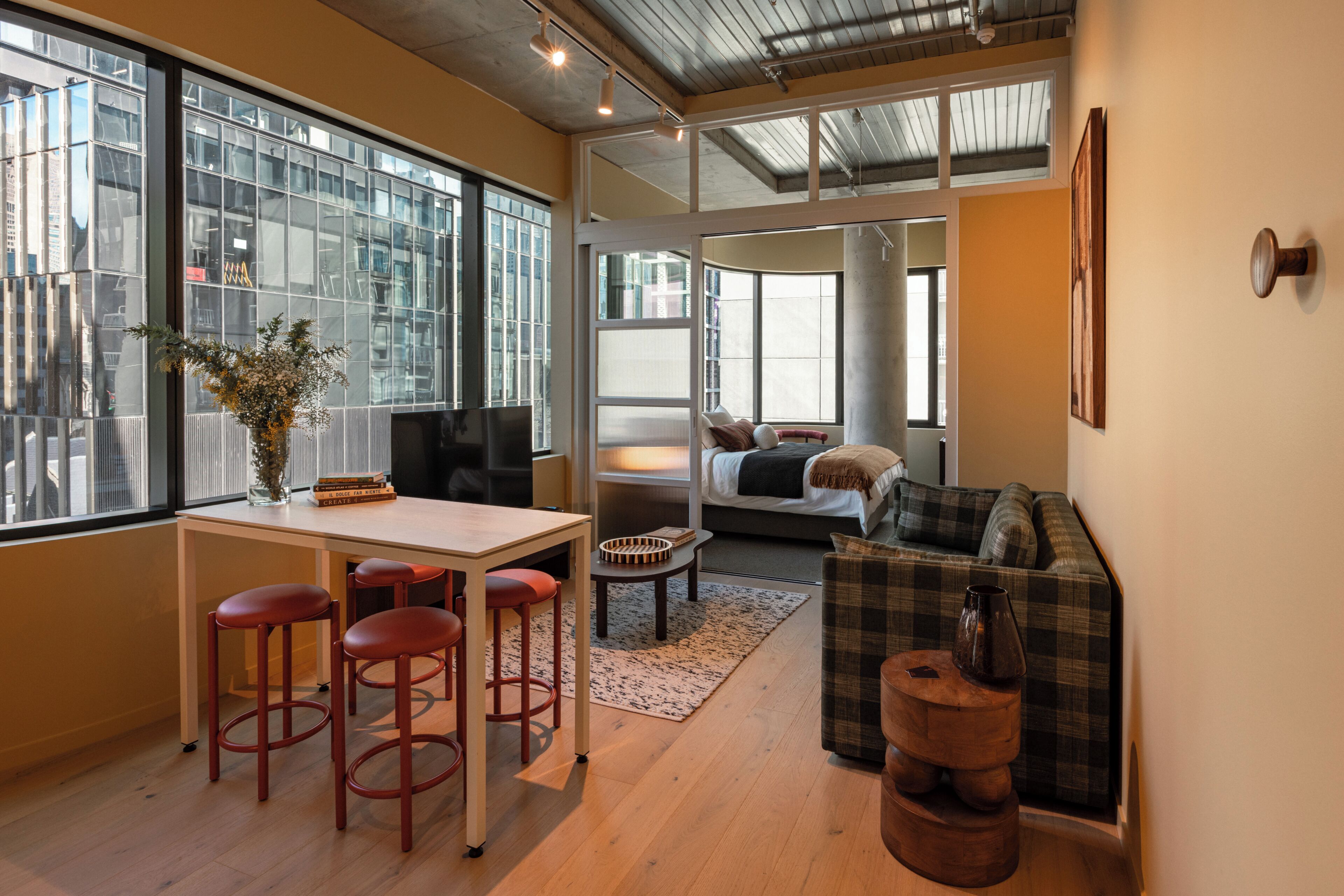 A modern interior with a dining area, seating, and a view of the city.