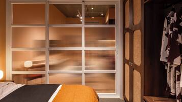 A hotel room with a bed, a wardrobe, and a sliding door with vertical blinds.