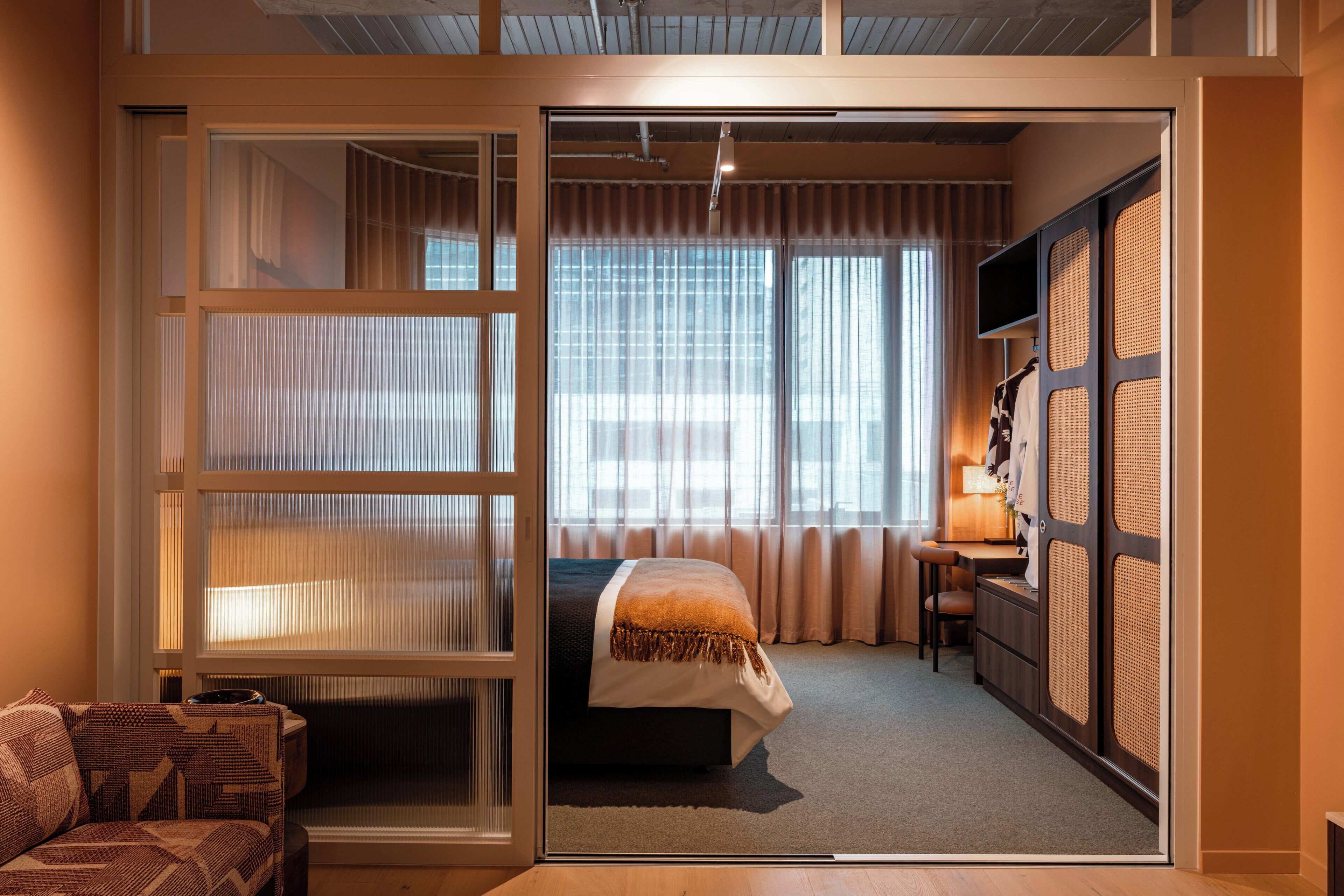 Une chambre d’hôtel équipée d’un lit, d’un bureau, d’une chaise et d’une porte-fenêtre coulissante donnant sur un balcon.