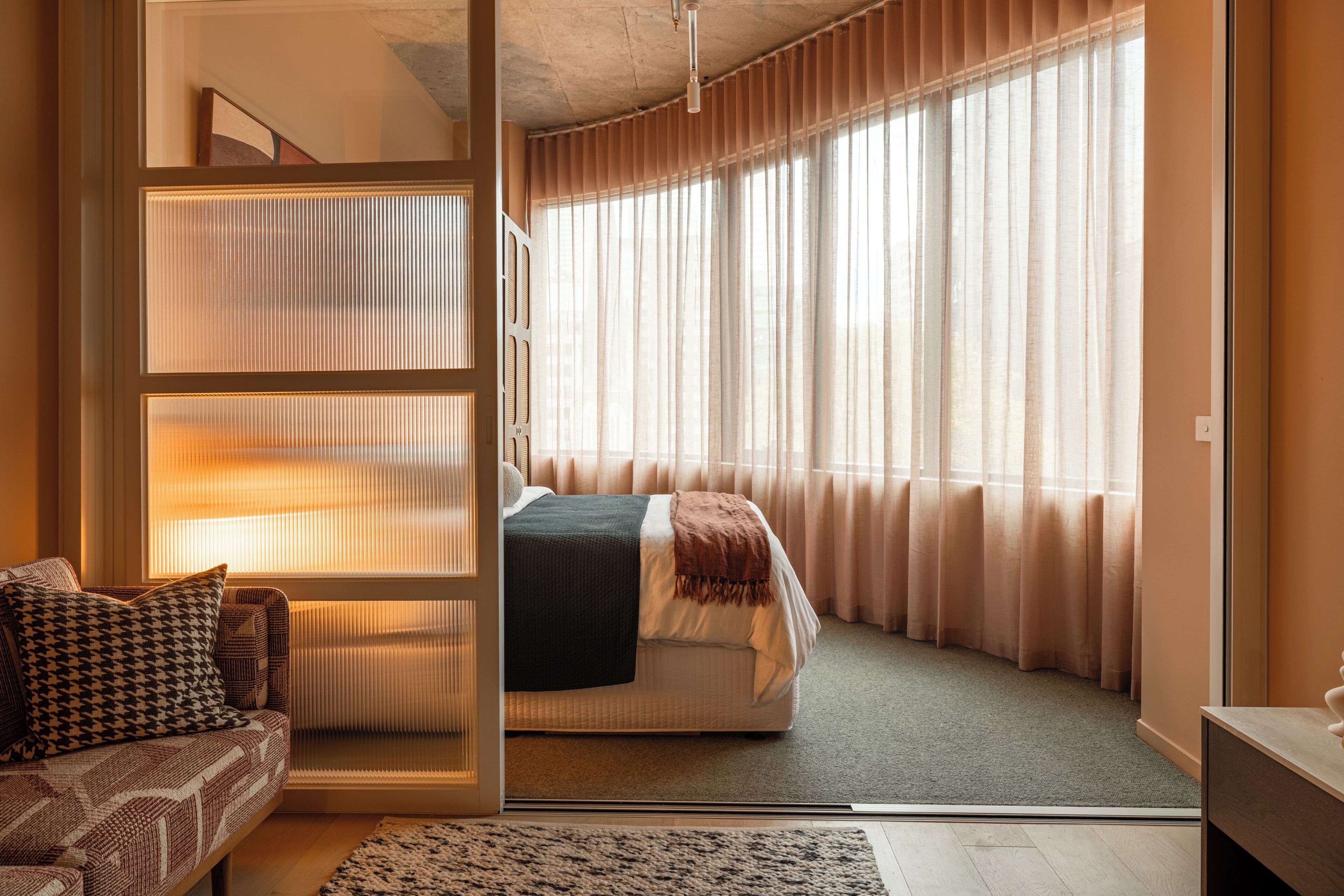 Une chambre à coucher avec un lit, un canapé et une grande fenêtre avec des rideaux.