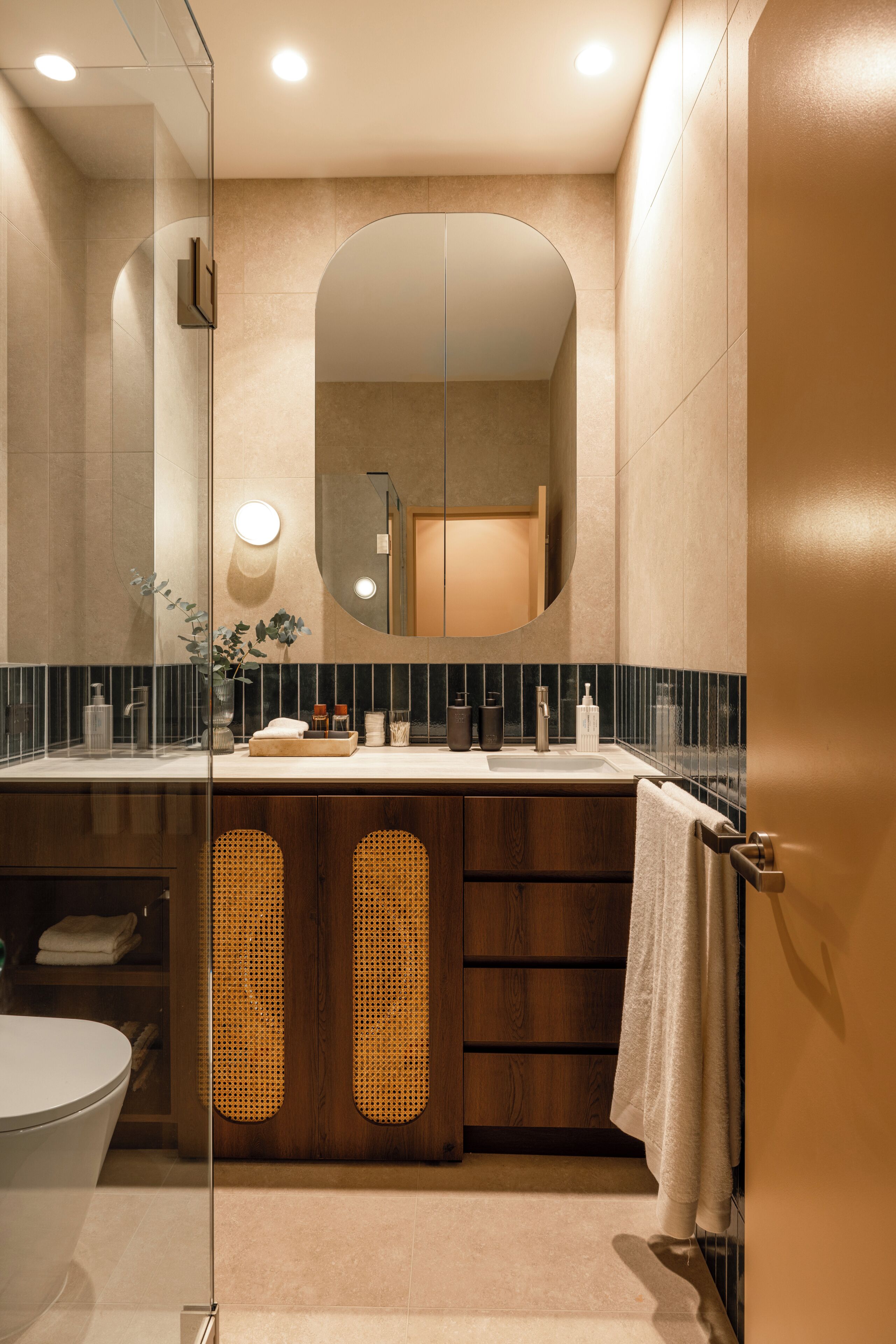 A modern bathroom with a glass shower enclosure, a wooden vanity, and a large mirror.