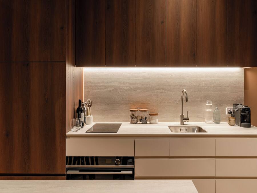 A modern kitchen with wooden cabinets, a stainless steel sink, and a built-in wine cooler.