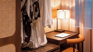 A hotel room with a wooden desk, a laptop, a lamp, and a clothing rack with robes. - The Lane House (Melbourne)