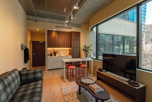A modern living room with a sofa, a coffee table, and a large window offering a city view.