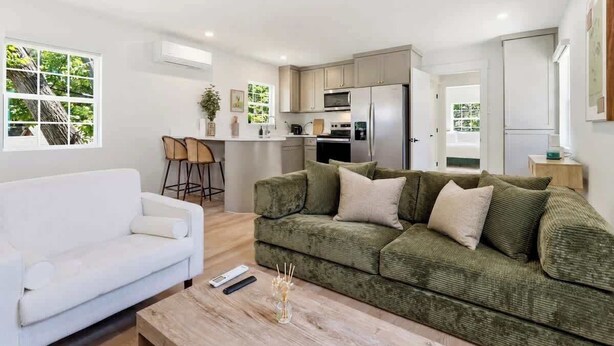 Ein modernes Wohnzimmer mit einem weißen Sofa, einem grünen Sofa und einem Couchtisch aus Holz.