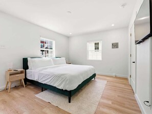 A bedroom with a bed, bedside table, and a window. - Modern 1BR on Main St in Bishop Arts (Dallas)