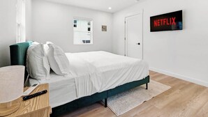 Ein modernes Hotelzimmer mit einem Einzelbett, einem an der Wand montierten Fernseher und einem Fenster mit Blick.