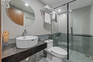 Un bagno moderno con uno specchio rotondo, un lavandino bianco, il water e una cabina doccia in vetro.